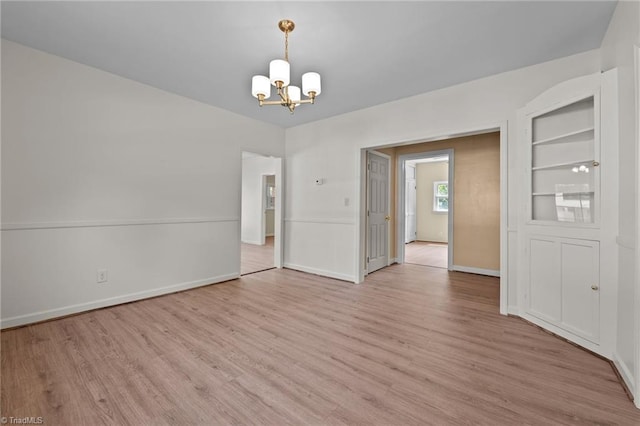 empty room with a chandelier and light hardwood / wood-style floors