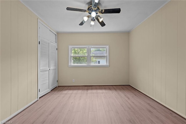 unfurnished bedroom with light wood-type flooring, ornamental molding, ceiling fan, and a closet