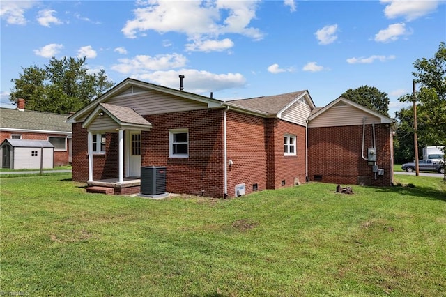 rear view of house featuring central AC unit, a lawn, and a storage unit