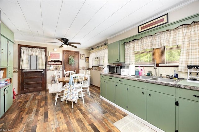 kitchen featuring green cabinetry, stainless steel microwave, a sink, dark wood-style flooring, and a ceiling fan