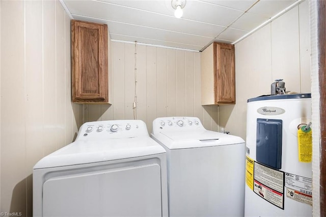laundry area featuring wood walls, washer and dryer, electric water heater, and cabinet space