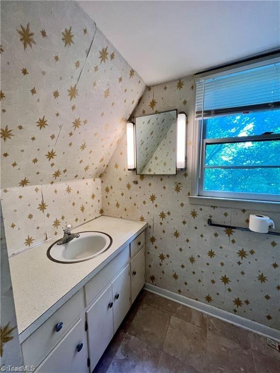 bathroom with tile patterned flooring, vaulted ceiling, and vanity