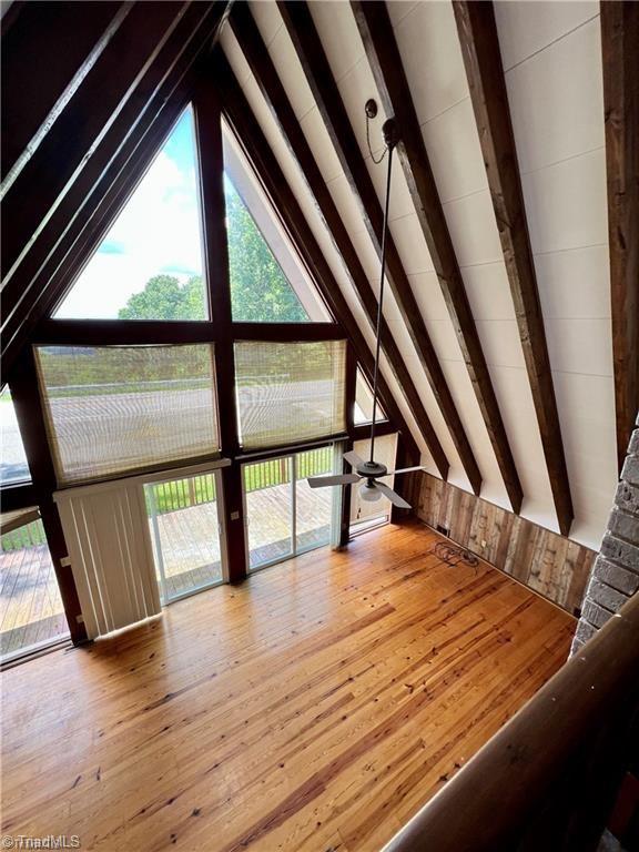 interior space featuring a wealth of natural light, hardwood / wood-style flooring, vaulted ceiling with beams, and ceiling fan