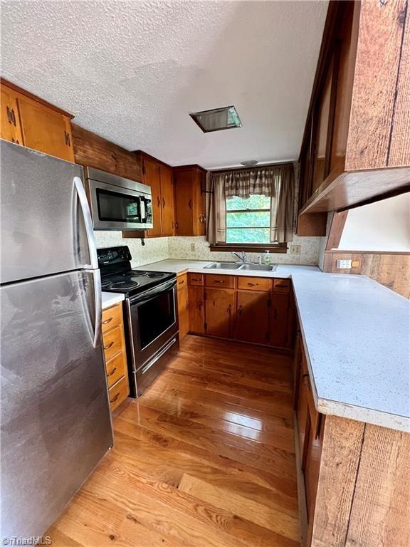 kitchen featuring light hardwood / wood-style floors, appliances with stainless steel finishes, sink, and a textured ceiling