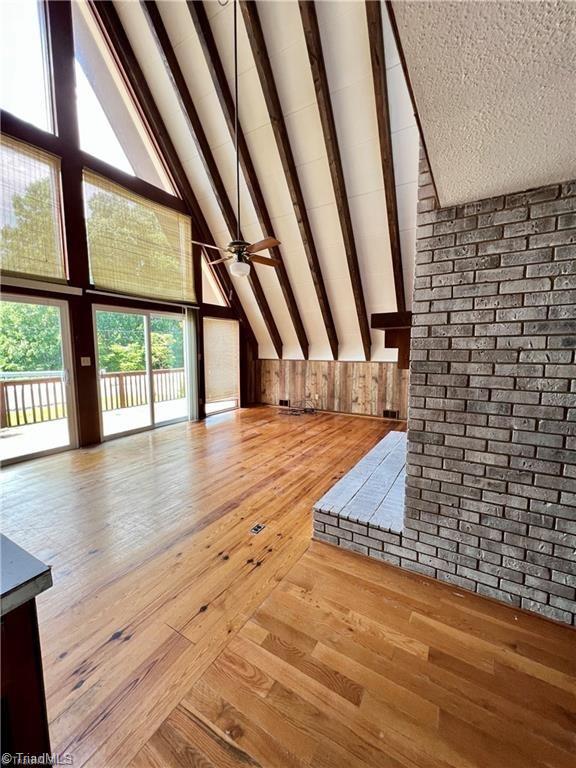 interior space with high vaulted ceiling, beamed ceiling, ceiling fan, and light hardwood / wood-style flooring