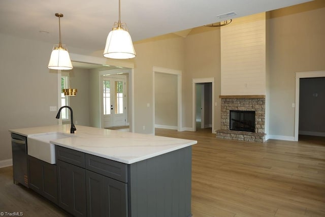 kitchen featuring a sink, gray cabinets, open floor plan, dishwasher, and baseboards