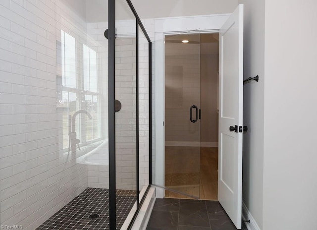 full bath featuring a stall shower, baseboards, and marble look tiles