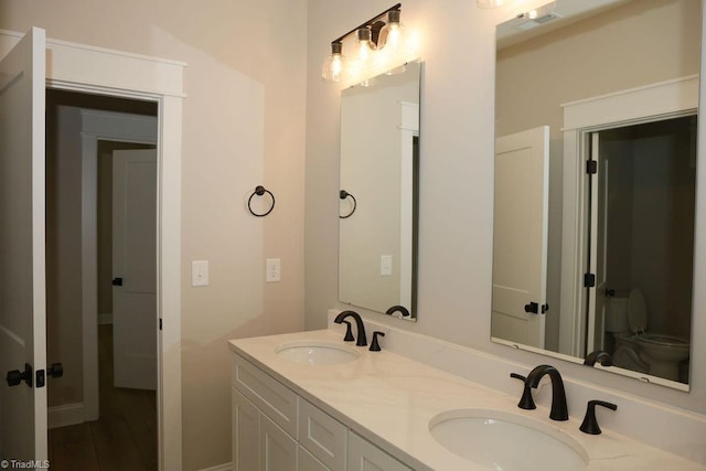 full bath with double vanity and toilet