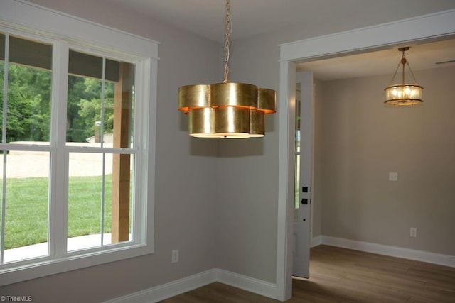 unfurnished dining area with healthy amount of natural light, wood finished floors, and baseboards