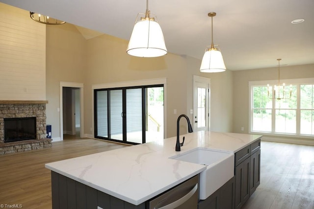 kitchen featuring stainless steel dishwasher, open floor plan, a chandelier, a sink, and light wood-style floors