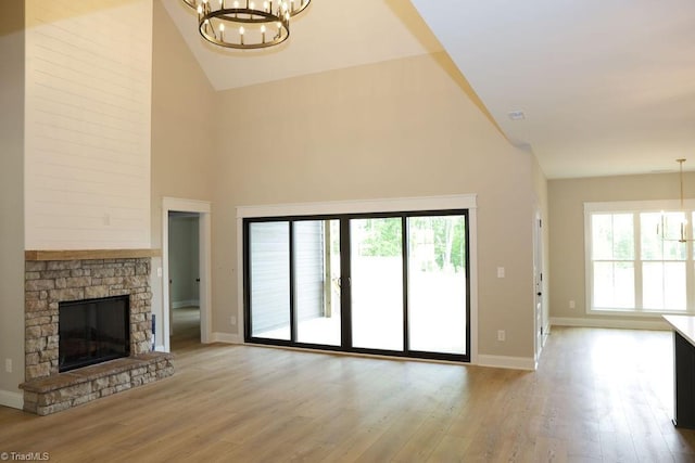 unfurnished living room with a chandelier, high vaulted ceiling, baseboards, and plenty of natural light
