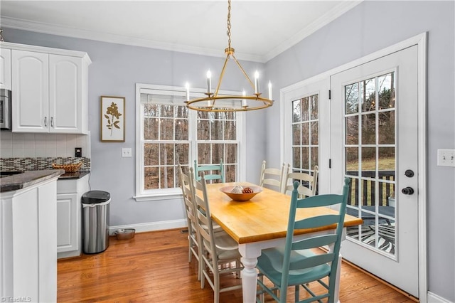 dining area featuring crown molding, a notable chandelier, and light wood-type flooring