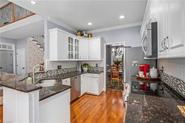 kitchen with white cabinetry, stainless steel appliances, sink, backsplash, and kitchen peninsula