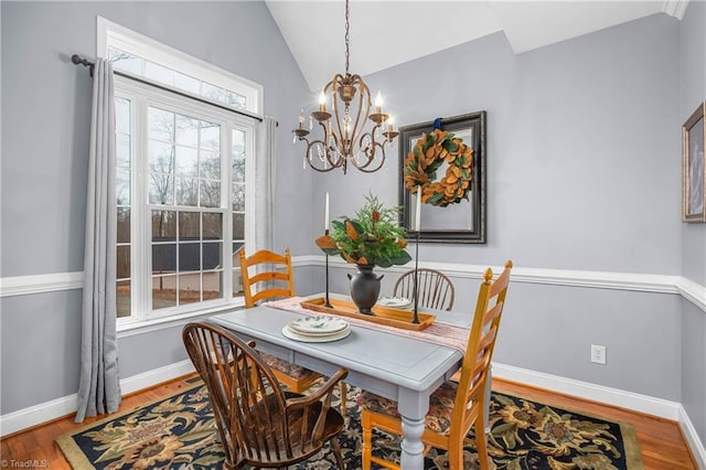 dining space with hardwood / wood-style flooring, a chandelier, and vaulted ceiling