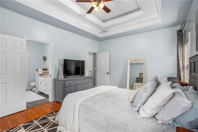 bedroom featuring ensuite bath, light hardwood / wood-style floors, ornamental molding, a raised ceiling, and ceiling fan