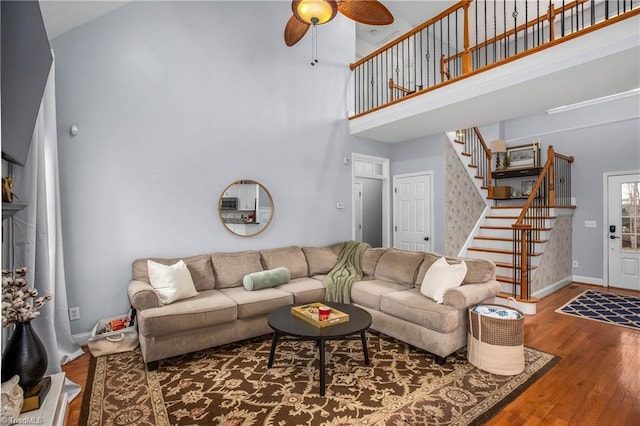 living room with wood-type flooring, a high ceiling, and ceiling fan