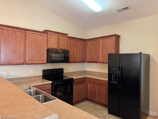 4373 Rex Ct, Winston-Salem, NC 27107 - kitchen featuring black appliances, a sink, vaulted ceiling, and light countertops
