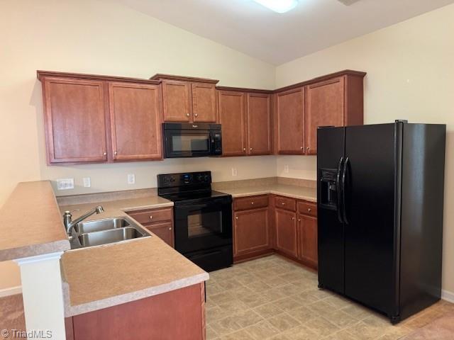 4373 Rex Ct, Winston-Salem, NC 27107 - kitchen with black appliances, a sink, a peninsula, vaulted ceiling, and brown cabinets