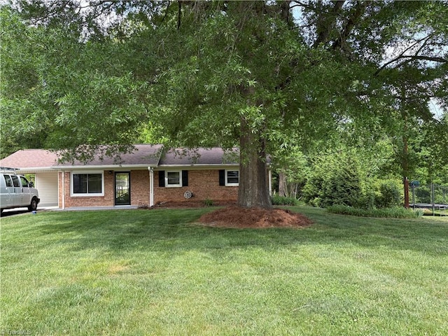 single story home with brick siding, a trampoline, and a front yard