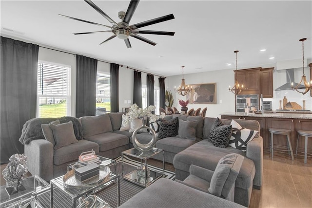 living room featuring ceiling fan with notable chandelier and light hardwood / wood-style flooring