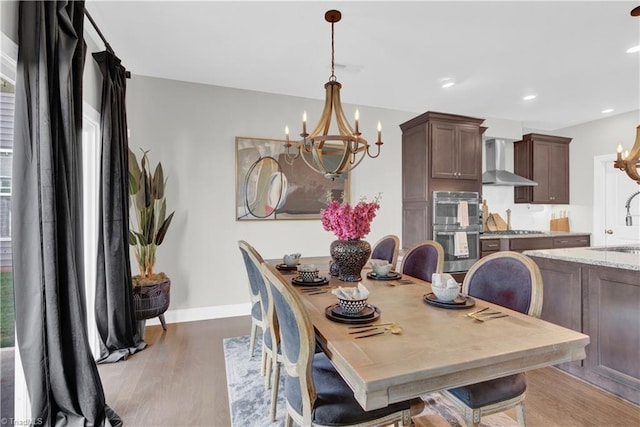 dining room with sink, light hardwood / wood-style floors, and a notable chandelier