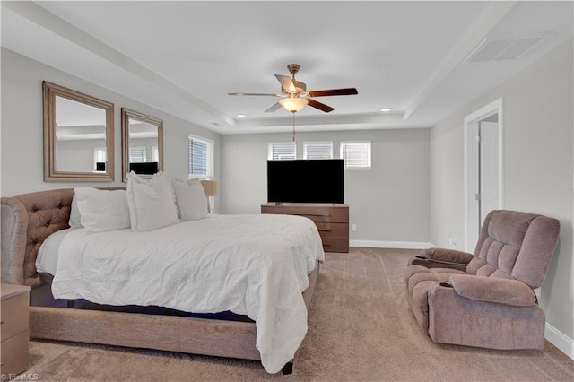 bedroom with ceiling fan, light colored carpet, a tray ceiling, and multiple windows