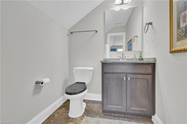 bathroom with toilet, lofted ceiling, and vanity