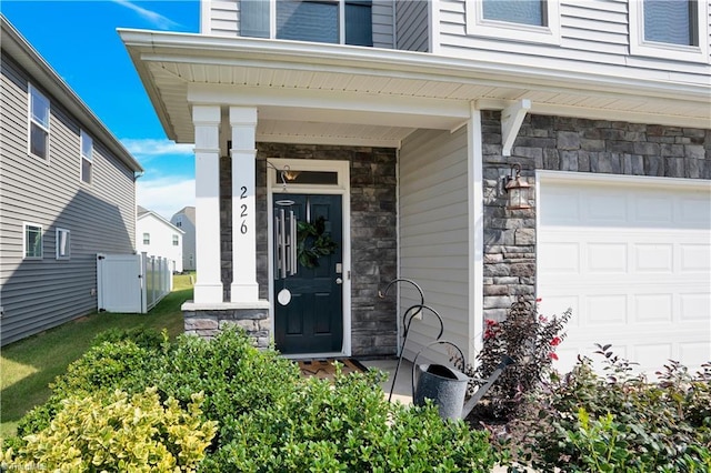 view of exterior entry with covered porch and a garage