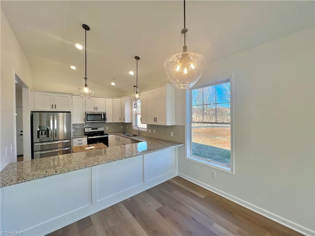 kitchen featuring kitchen peninsula, white cabinets, stainless steel appliances, and lofted ceiling