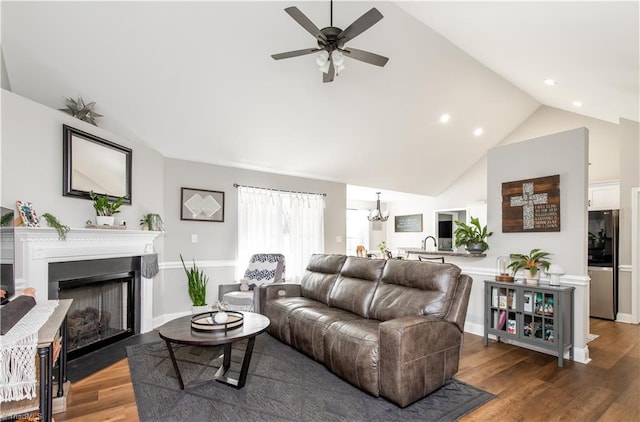 living room featuring high vaulted ceiling, ceiling fan with notable chandelier, and hardwood / wood-style flooring