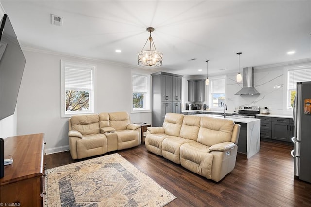 living room featuring dark wood-type flooring, sink, crown molding, and an inviting chandelier