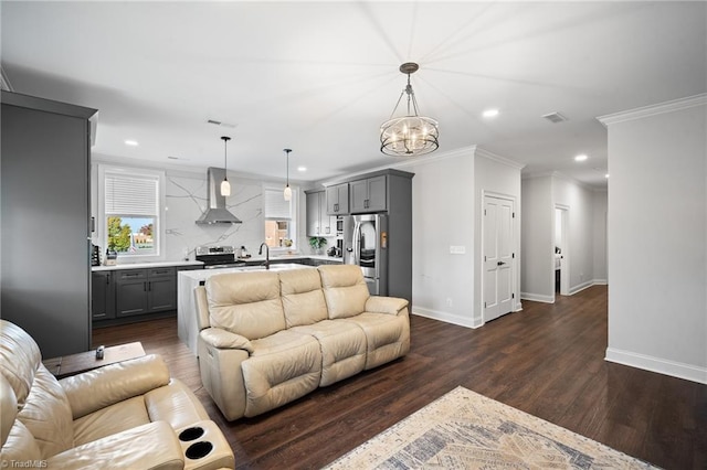 living room with dark hardwood / wood-style flooring, sink, an inviting chandelier, and ornamental molding