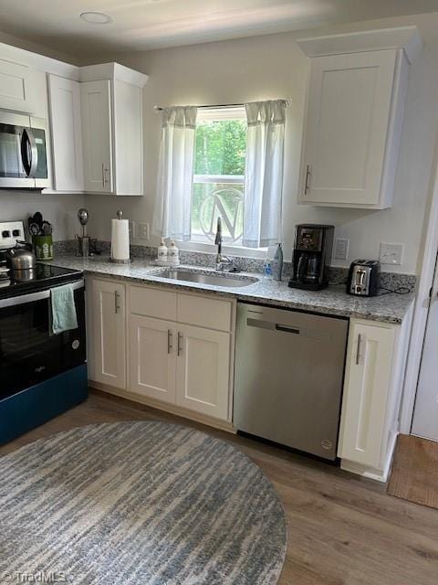 545 S Fieldcrest Rd, Eden, NC 27288 - kitchen with stainless steel appliances, a sink, white cabinets, light wood-style floors, and light stone counters