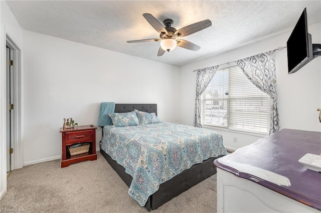 bedroom with light carpet, ceiling fan, a textured ceiling, and baseboards