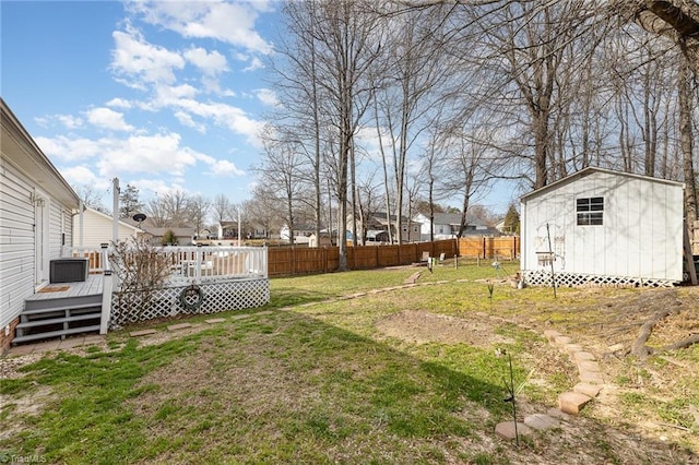 view of yard featuring a storage shed, fence, a deck, and an outdoor structure