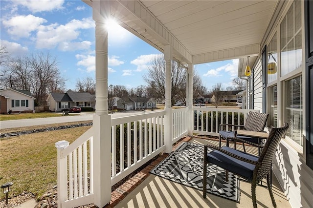 balcony featuring covered porch, a sunroom, and a residential view