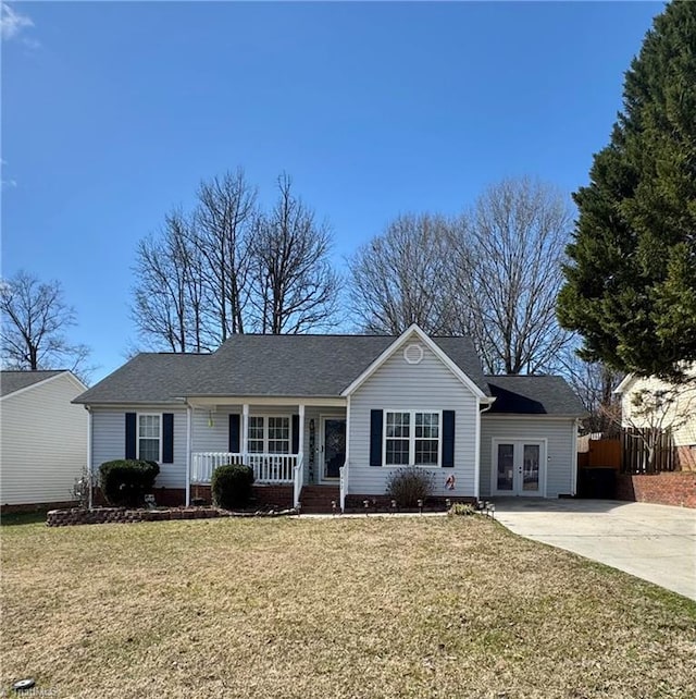 ranch-style home featuring a porch, concrete driveway, fence, and a front lawn