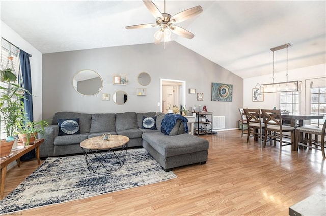 living area with ceiling fan, high vaulted ceiling, visible vents, baseboards, and light wood finished floors