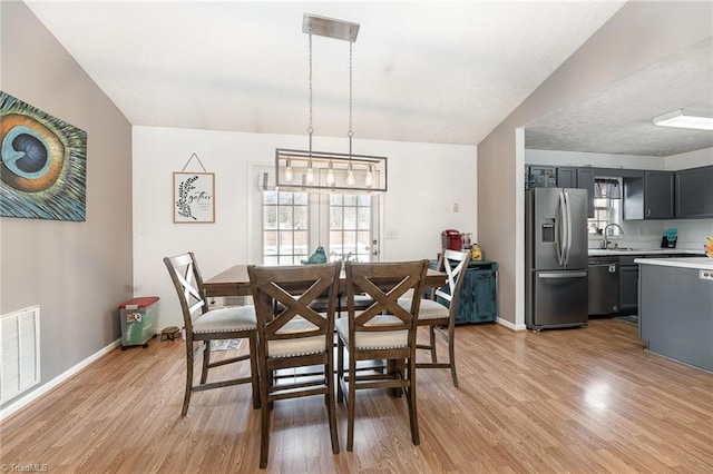 dining area with light wood-type flooring, visible vents, and baseboards