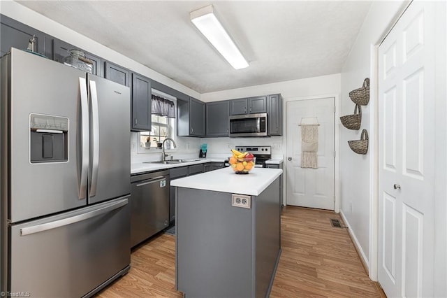 kitchen featuring appliances with stainless steel finishes, light wood-style floors, light countertops, and a sink