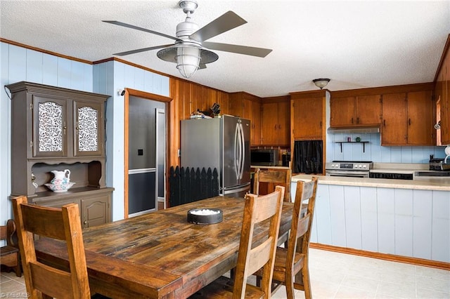 dining area featuring crown molding, a ceiling fan, wooden walls, and a textured ceiling