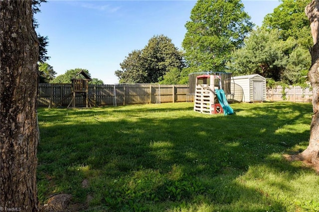 view of yard with an outdoor structure, a fenced backyard, a playground, and a shed