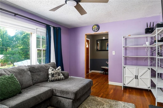 living area with baseboards, a textured ceiling, ceiling fan, and wood finished floors