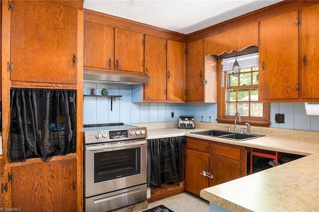 kitchen featuring a sink, brown cabinetry, under cabinet range hood, and stainless steel range with electric cooktop