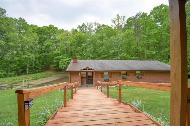 wooden deck featuring a lawn and a wooded view