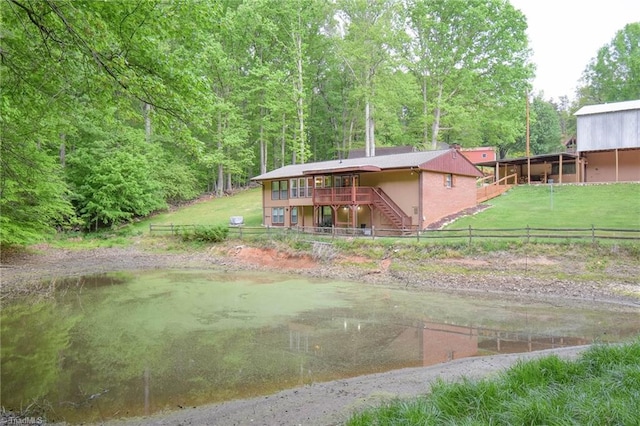 exterior space with fence private yard, a wooden deck, stairs, a lawn, and a forest view