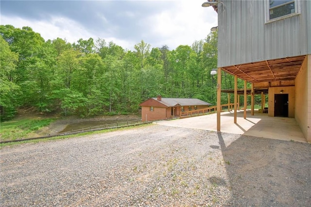 view of patio with a carport, gravel driveway, and a forest view