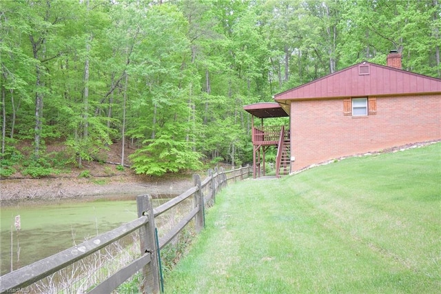 view of yard with stairway, a deck, fence, and a forest view