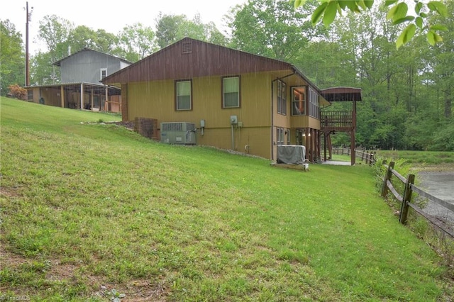 view of side of home featuring fence, a yard, and central AC