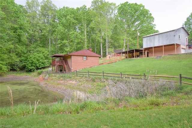 view of yard featuring a forest view, fence, and stairs